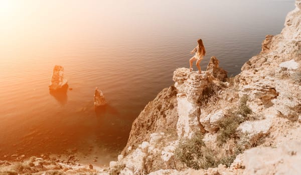 Woman travel sea. Happy tourist taking picture outdoors for memories. Woman traveler looks at the edge of the cliff on the sea bay of mountains, sharing travel adventure journey.