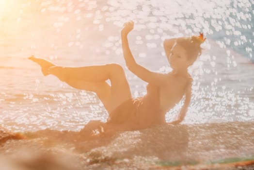 Side view a Young beautiful sensual woman in a red long dress posing on a rock high above the sea during sunrise. Girl on the nature on blue sky background. Fashion photo.