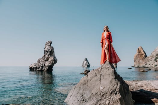 Woman travel sea. Happy tourist taking picture outdoors for memories. Woman traveler looks at the edge of the cliff on the sea bay of mountains, sharing travel adventure journey.