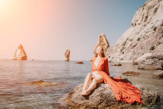 Woman travel sea. Happy tourist taking picture outdoors for memories. Woman traveler looks at the edge of the cliff on the sea bay of mountains, sharing travel adventure journey.