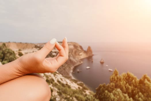 Middle aged well looking woman with black hair doing Pilates with the ring on the yoga mat near the sea on the pebble beach. Female fitness yoga concept. Healthy lifestyle, harmony and meditation.