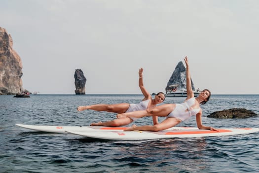 Woman sup yoga. Middle age sporty woman practising yoga pilates on paddle sup surfboard. Female stretching doing workout on sea water. Modern individual hipster outdoor summer sport activity