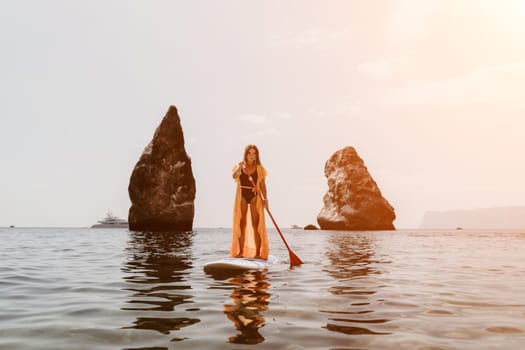 Close up shot of beautiful young caucasian woman with black hair and freckles looking at camera and smiling. Cute woman portrait in a pink bikini posing on a volcanic rock high above the sea