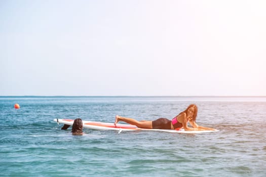 Silhouette of woman standing, surfing on SUP board, confident paddling through water surface. Idyllic sunset or sunrise. Sports active lifestyle at sea or river.