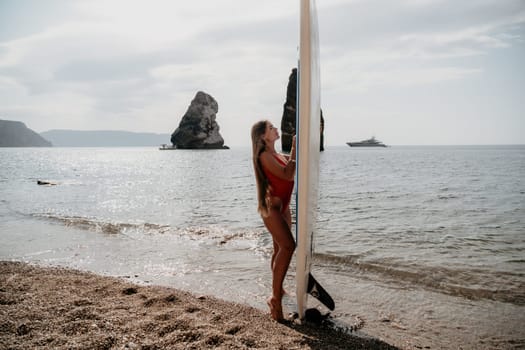 Close up shot of beautiful young caucasian woman with black hair and freckles looking at camera and smiling. Cute woman portrait in a pink bikini posing on a volcanic rock high above the sea