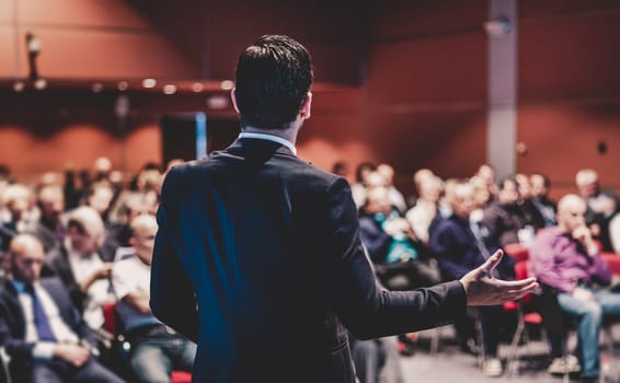 Speaker at Business Conference with Public Presentations. Audience at the conference hall. Entrepreneurship club. Rear view. Panoramic composition. Background blur.