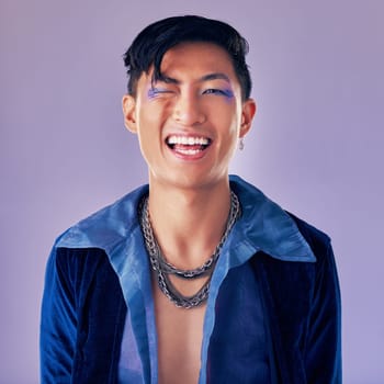 Punk, rock and makeup of a man with a smile for metal music, lifestyle and identity against a purple studio background. Freedom, crazy and face portrait of a cyberpunk Asian person with cosmetics.
