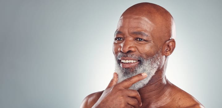 Senior black man, smile and beard in skincare for facial treatment, cosmetics or thinking on mockup. Happy elderly African American male smiling face in satisfaction against a grey studio background.