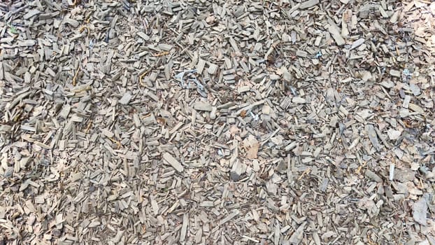 Abstract background and texture of sawdust and pieces of wood. Texture, pattern, frame, copy space. Brown or grey mulch used for gardening, landscape decoration