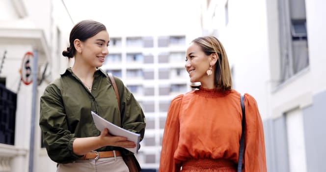 Outdoor, women and employees walking, documents and discussion for ideas, planning and teamwork. Female coworkers, staff and friends with paperwork, smile and communication outside with collaboration.