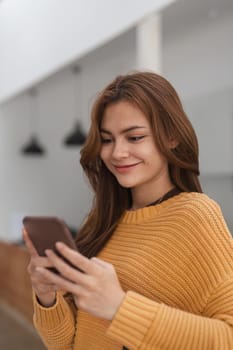 Happy young woman browsing surfing wireless internet on mobile phone at home, Shopping online via website.