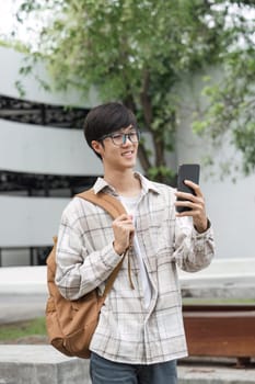 Male student holds up mobile phone to take pictures on campus.