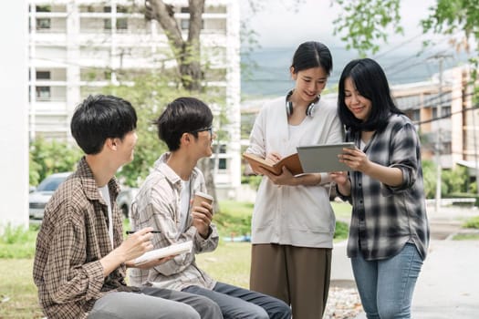 University students sitting together at table with books and laptop and tablet. Happy young people doing group study in university.