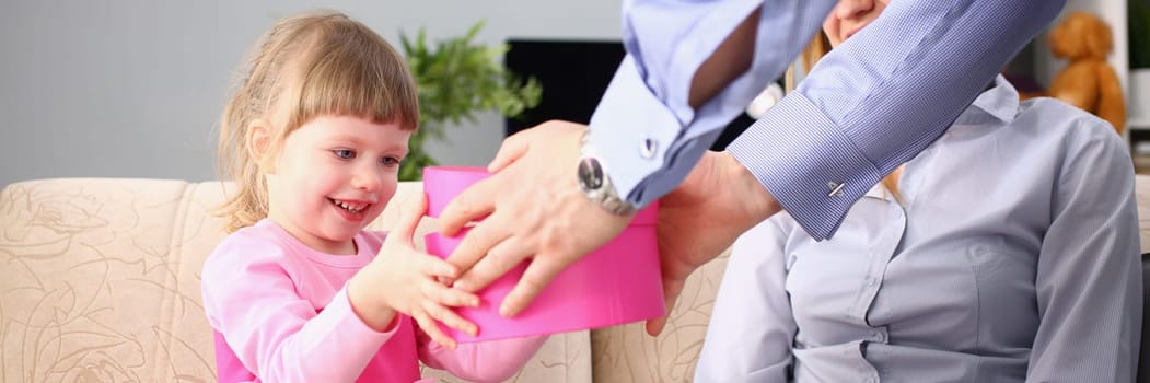 Parents give little girl child gift box. Surprise birthday and gift for daughter