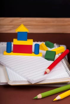 board, books, pencils, opened empty notebook against a dark background