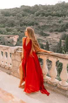 Woman red dress. Summer lifestyle of a happy woman posing near a fence with balusters over the sea