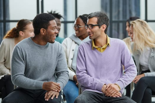 Young people enjoying spending time together on special group therapy. Handsome joyful guy talking jokes and making fun.