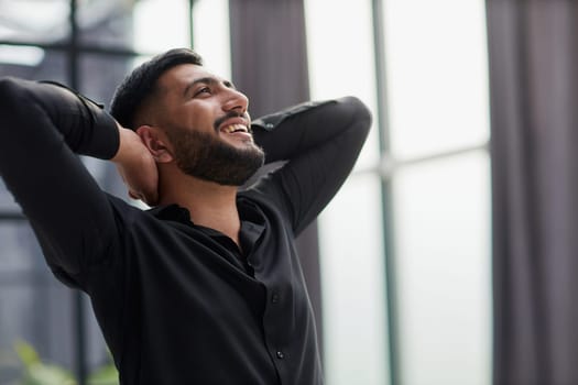 Portrait of relaxed businessman in modern office.Business young man relax after work of office window with business district view.