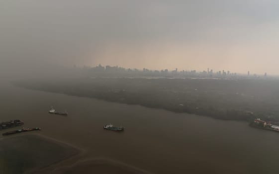 Bangkok, Thailand - May 28, 2023 - Misty Landscape of city skyscrapers covered before raining. Heavy dense smog fot during afternoon that Bangkok city cannot be seen clearly, Aerial top view of city on a foggy day, Space for text, No focus, specifically.