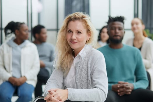 Business woman sitting on a chair with her staff in the background