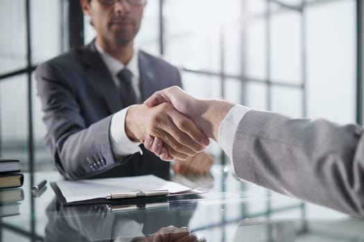 Man shaking hands with partner over office desk