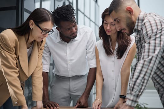 Diverse business groups stand around a meeting table.