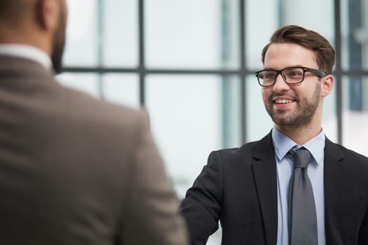 smiling businessmen shaking hands starting teamwork partnership standing in corporate work space hallway