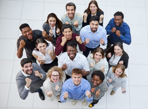 large group of young people looking up with clenched fists celebrating victory