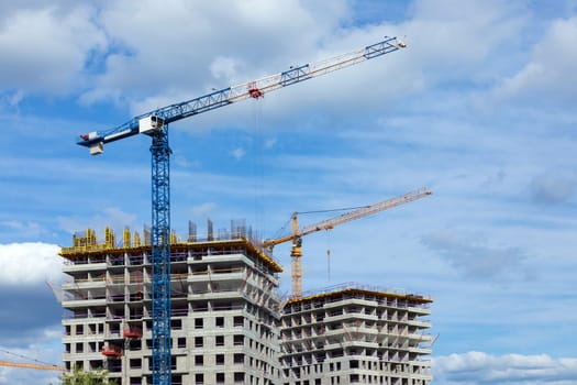 Crane and building under construction against blue sky