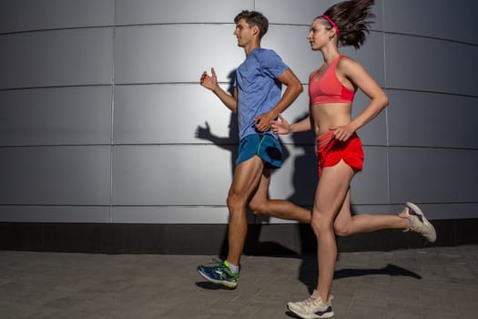 Active young couple jogging side by side in an urban street during their daily workout in a health and fitness concept. Healthy lifestyle