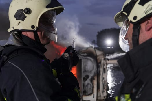 Firefighters using water fire extinguisher to fighting with the fire flame in car accident. Firefighter industrial and public safety concept rescue in night. High quality photo