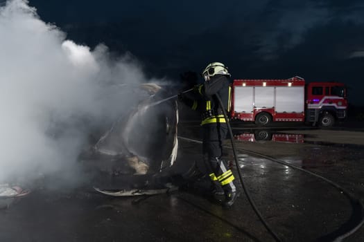 Firefighters using water fire extinguisher to fighting with the fire flame in car accident. Firefighter industrial and public safety concept rescue in night. High quality photo