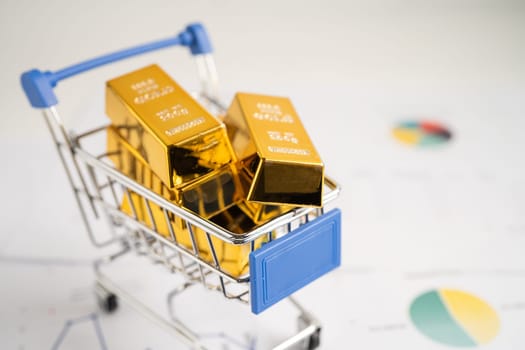 Gold bar in shopping cart on US dollar banknotes money and graph, economy finance exchange trade investment concept.