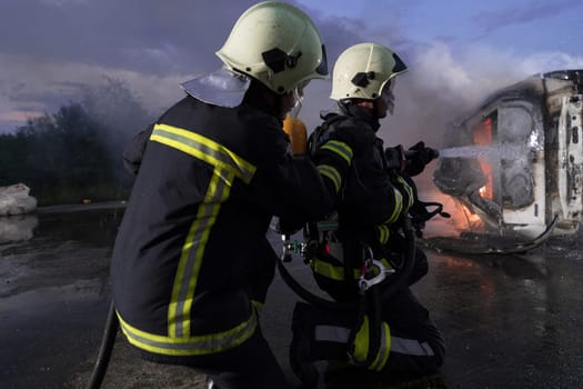 Firefighters using water fire extinguisher to fighting with the fire flame in car accident. Firefighter industrial and public safety concept rescue in night. High quality photo