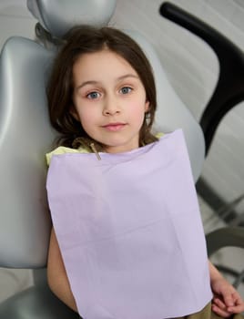Beautiful happy kid girl patient at dentist appointment for teeth cleaning, dental checkup and consultation. Pediatric dentistry. Oral care and hygiene. Diagnosis and prevention of baby teeth caries