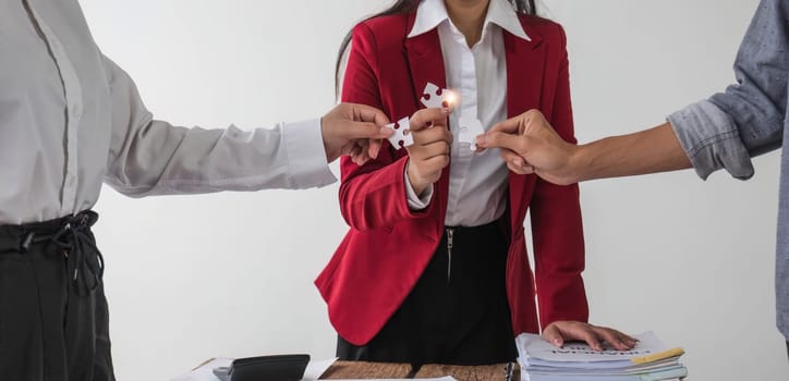 A group of business people assembling jigsaw puzzle. The concept of cooperation, teamwork, help and support in business...