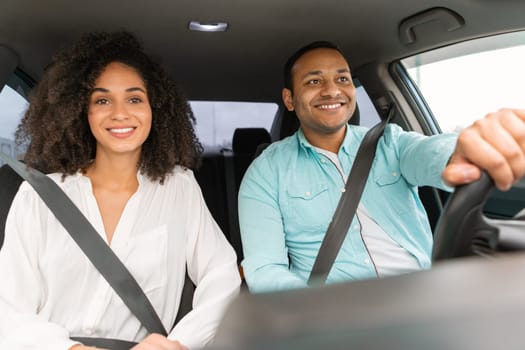 Cheerful middle eastern millennial couple having car trip, having summer weekend together sitting in automobile with fastened belts. Spouses enjoying auto ride, view from automobile dashboard