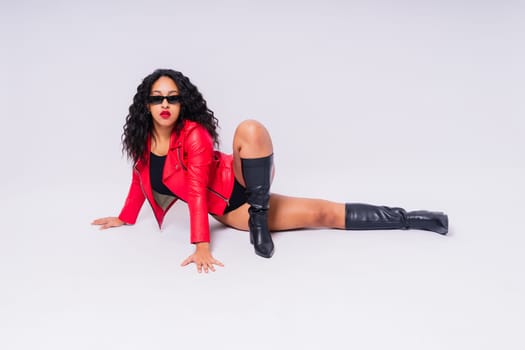 African American curvy female in black bodysuit and jacket on red and white background in a studio