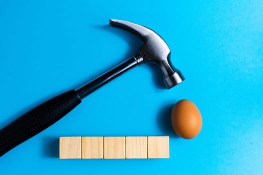 Hammer is hitting on egg with blue background. minimal idea creative concept.