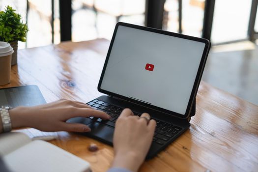 Chiang Mai, Thailand - AUG 23, 2021 : Woman using a tablet to connect to YouTube Premium. YouTube is a video-sharing website.