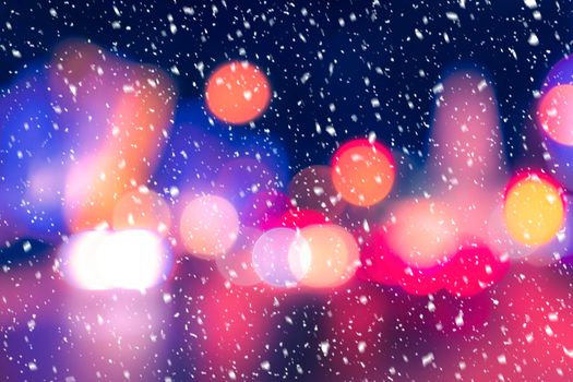 Blurred lights of headlights of cars and lanterns in the night city in a snowfall. Abstract bright bokeh.