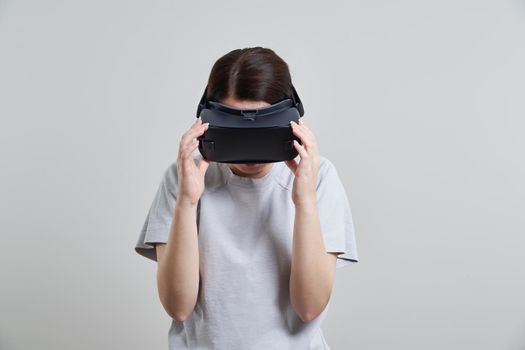 Happy young woman playing on VR glasses indoor. Virtual reality concept with young girl having fun with headset goggles.