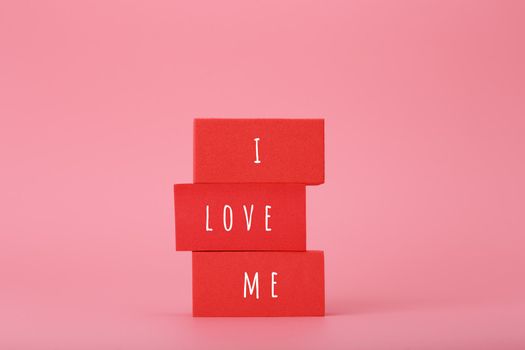 I love me creative concept of self love and mental health or being single. Stack of red blocks against pink background