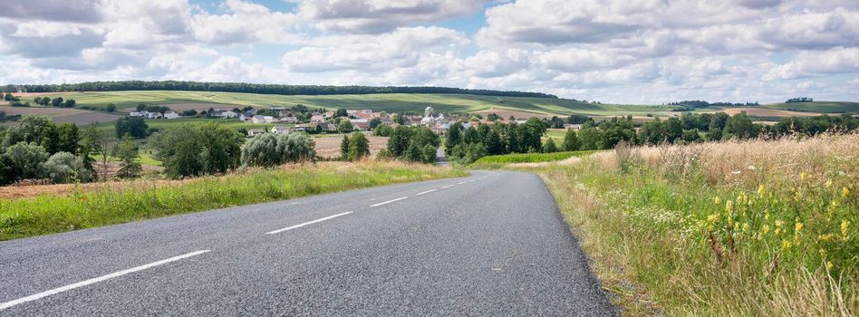 fields, villages and rolling hills in french countryside south of reims under blue sky in summer