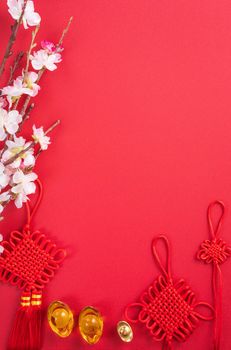 Design concept of Chinese lunar new year - Beautiful Chinese knot with plum blossom isolated on red background, flat lay, top view, overhead layout.