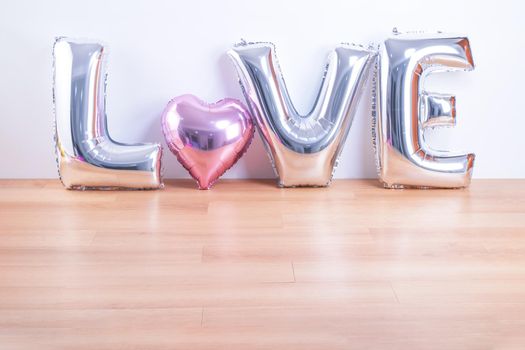 Valentine's day, Mother's day design concept - Beautiful balloon with word love shape on a light wooden floor and white wall background, close up.