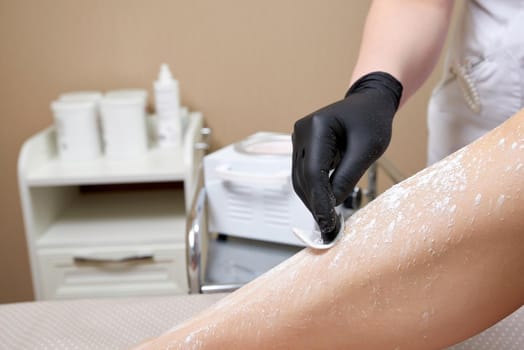 Beautician getting ready to wax female legs in spa center