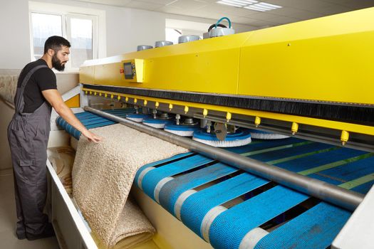 Man operating carpet automatic washing machine in professional cleaning service