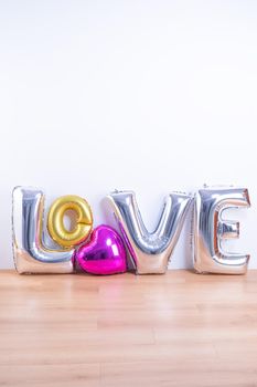 Valentine's day, Mother's day design concept - Beautiful balloon with word love shape on a light wooden floor and white wall background, close up.