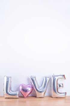 Valentine's day, Mother's day design concept - Beautiful balloon with word love shape on a light wooden floor and white wall background, close up.